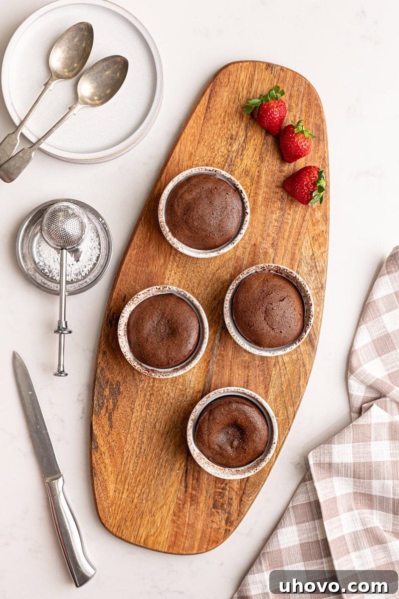 An inviting overhead view of four freshly baked chocolate lava cakes, each showcasing a beautifully set exterior and promising a rich, molten center, presented on a baking sheet.