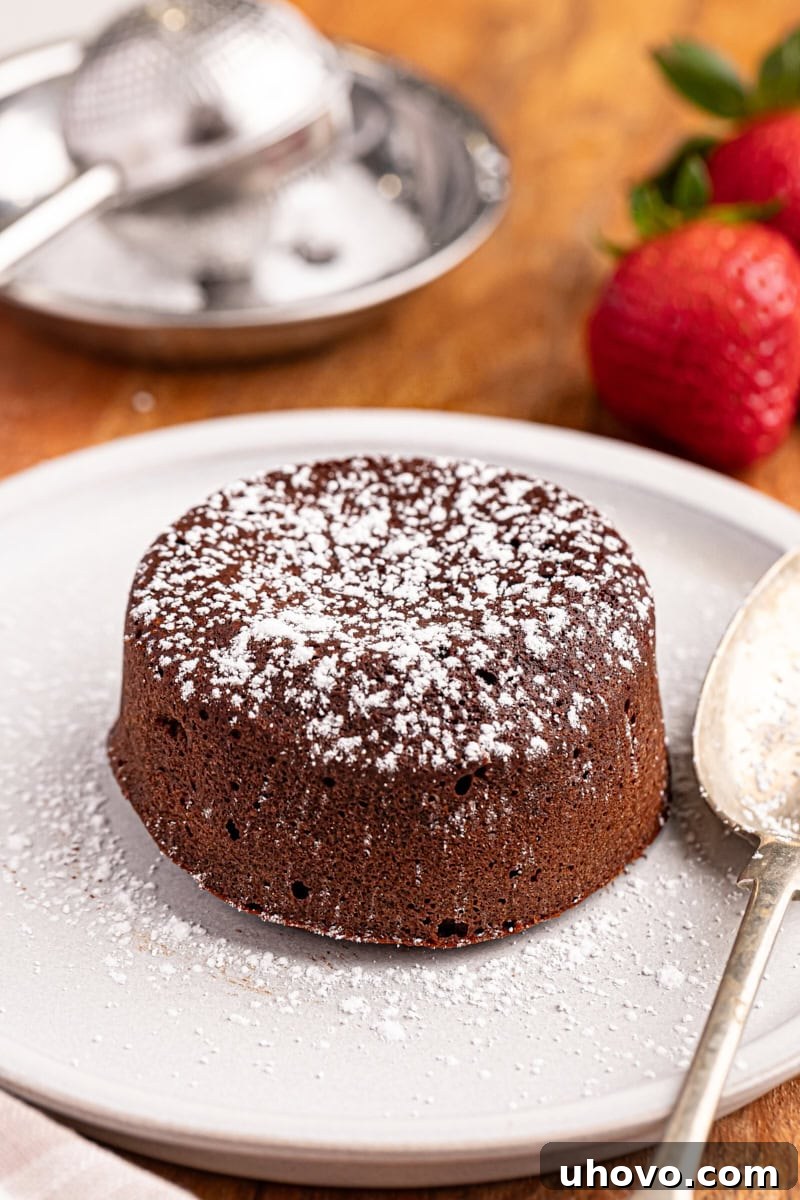 A beautifully presented chocolate lava cake, elegantly dusted with a generous layer of confectioners' sugar, served on a crisp white plate, ready for enjoyment.