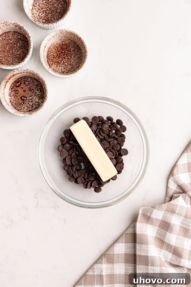 A close-up, overhead view of a glass bowl filled with chunks of dark chocolate and pats of unsalted butter, ready to be melted together for the lava cake mixture.