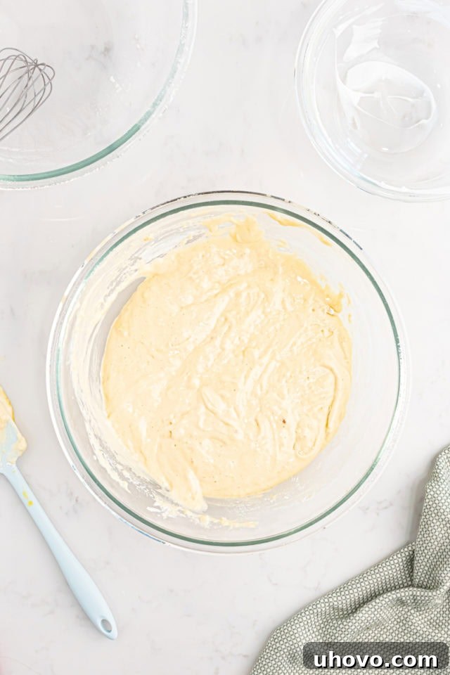 Overhead shot of the tres leches cake batter in a mixing bowl, showing its light and fluffy consistency after folding.