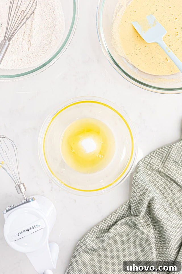 Overhead view of glistening egg whites and granulated sugar being whipped to perfection in a mixing bowl, illustrating the stiff peak stage.