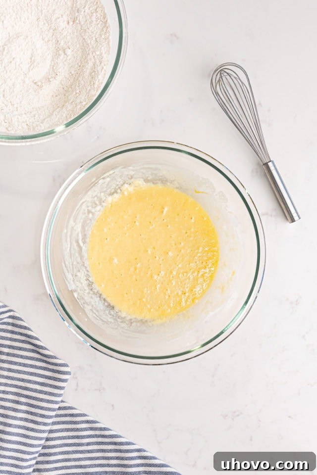 Overhead view of whisked buttermilk, melted butter, eggs, and vanilla extract in a separate bowl, showing the combined wet ingredients.