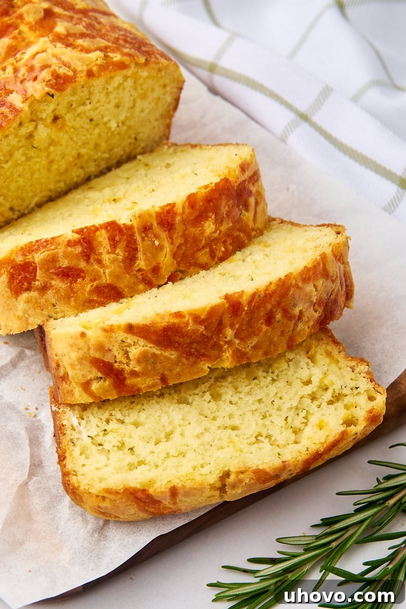 sliced herb and cheese quick bread on parchment paper, showcasing golden crust and cheesy interior
