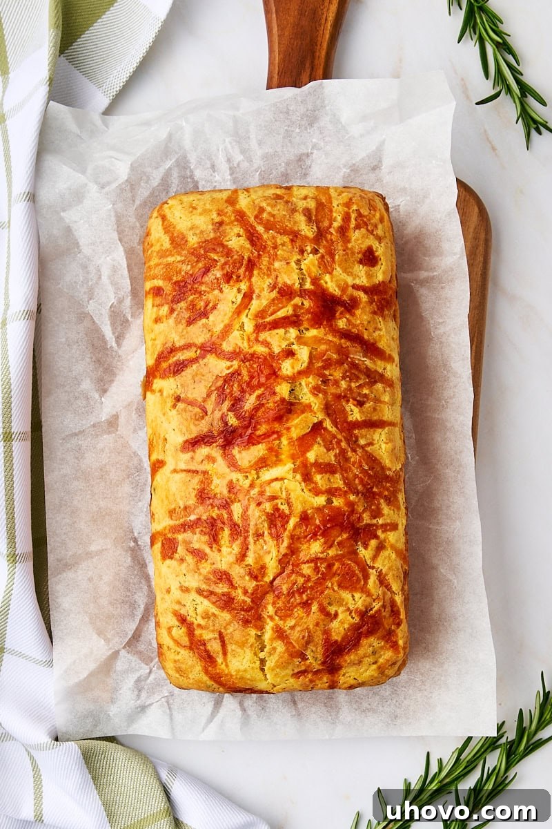 overhead view of herb and cheese quick bread on parchment paper on a wooden cutting board