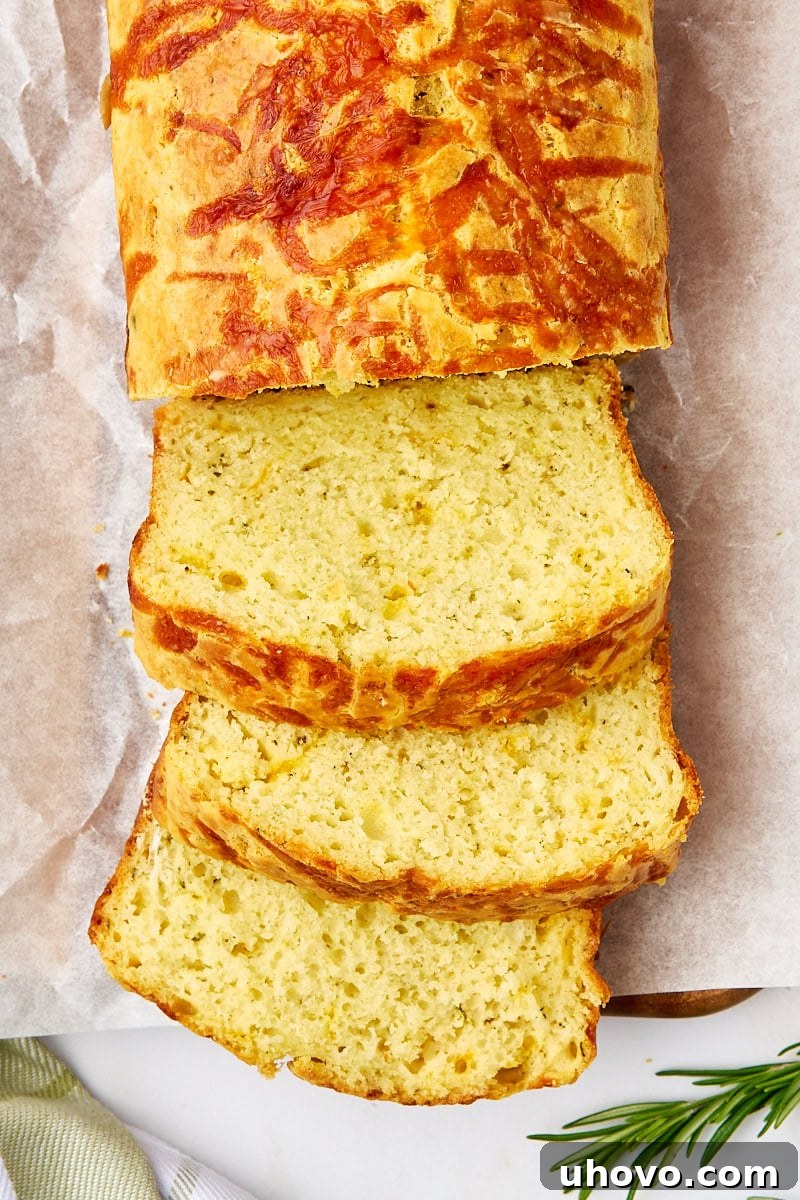 overhead view of partially sliced herb and cheese quick bread on parchment paper