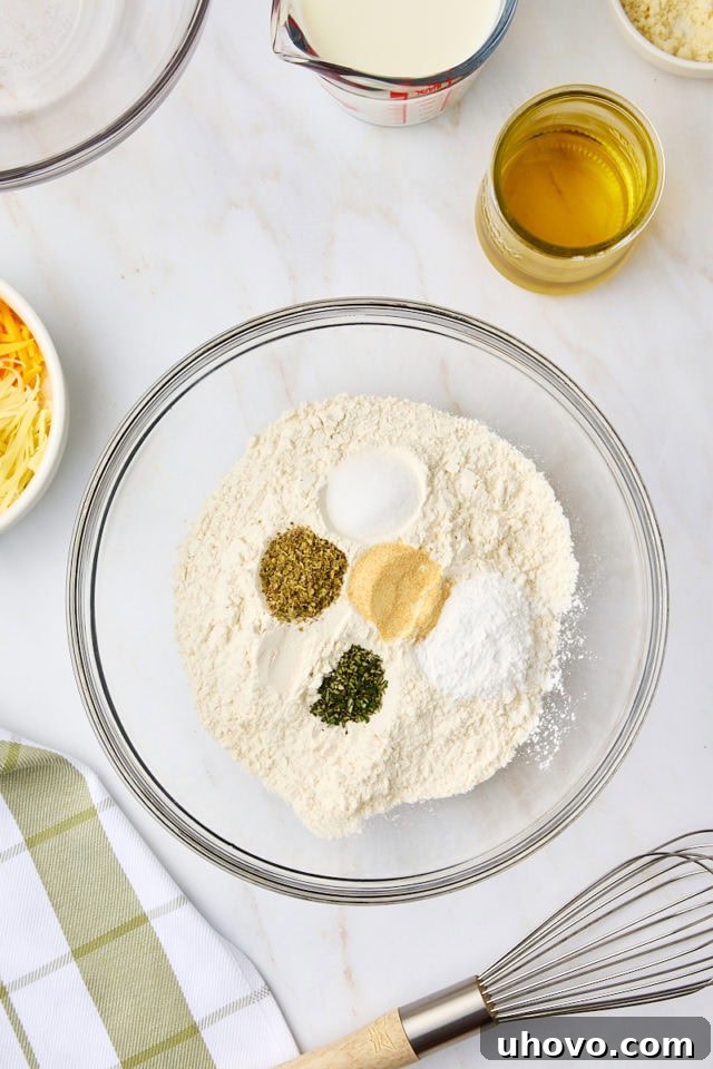 overhead view of flour, baking powder, garlic, and herbs in a mixing bowl