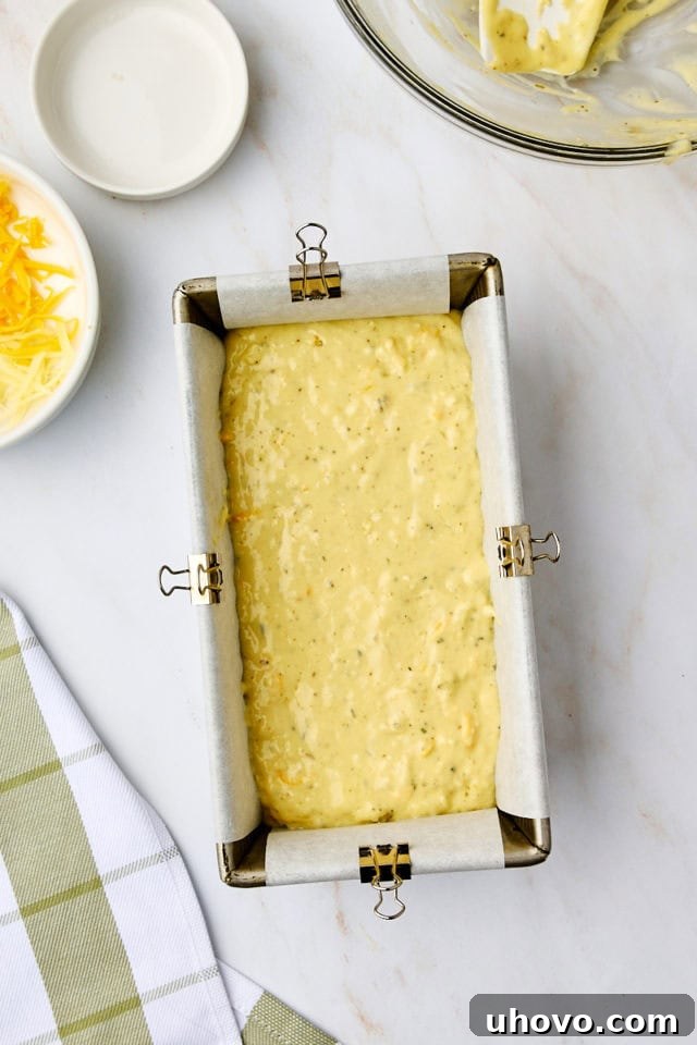 overhead view of herb and cheese quick bread batter in a loaf pan lined with parchment paper