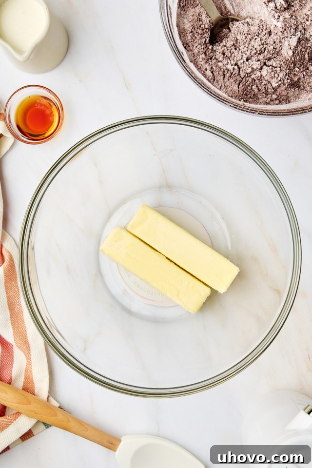 Softened unsalted butter being beaten in a mixing bowl until smooth and creamy for the chocolate frosting.