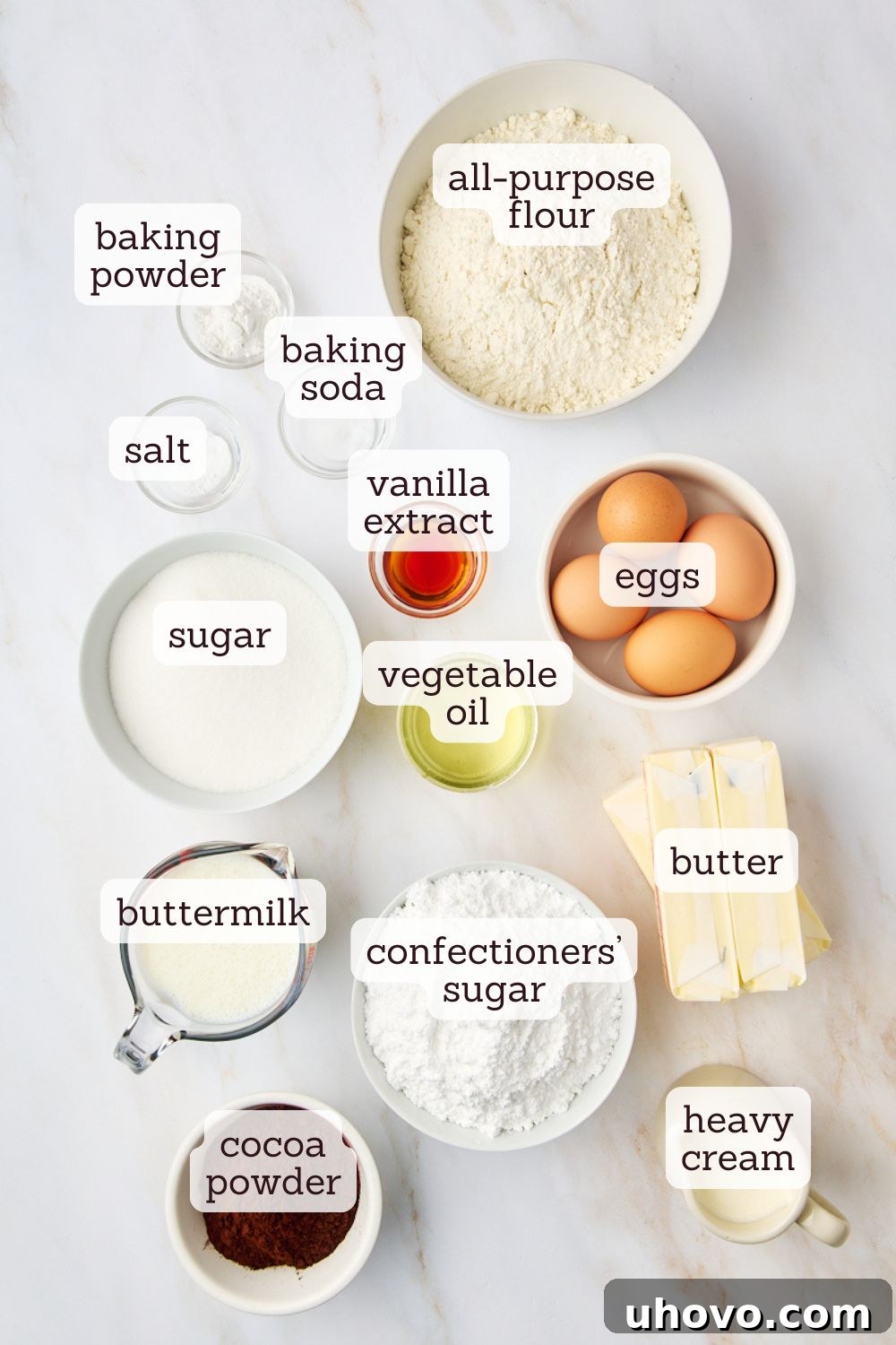 Overhead shot showcasing all the essential ingredients laid out for making a classic yellow cake with chocolate frosting, including flour, sugar, butter, eggs, and cocoa powder.