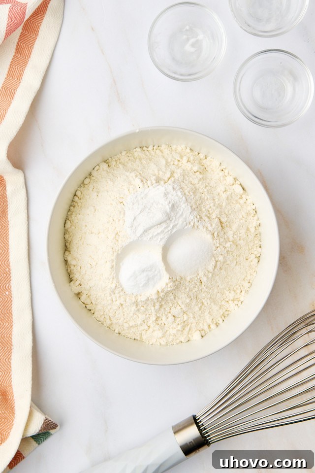 A bowl containing dry ingredients for yellow cake: flour, baking powder, baking soda, and salt, perfectly whisked together.