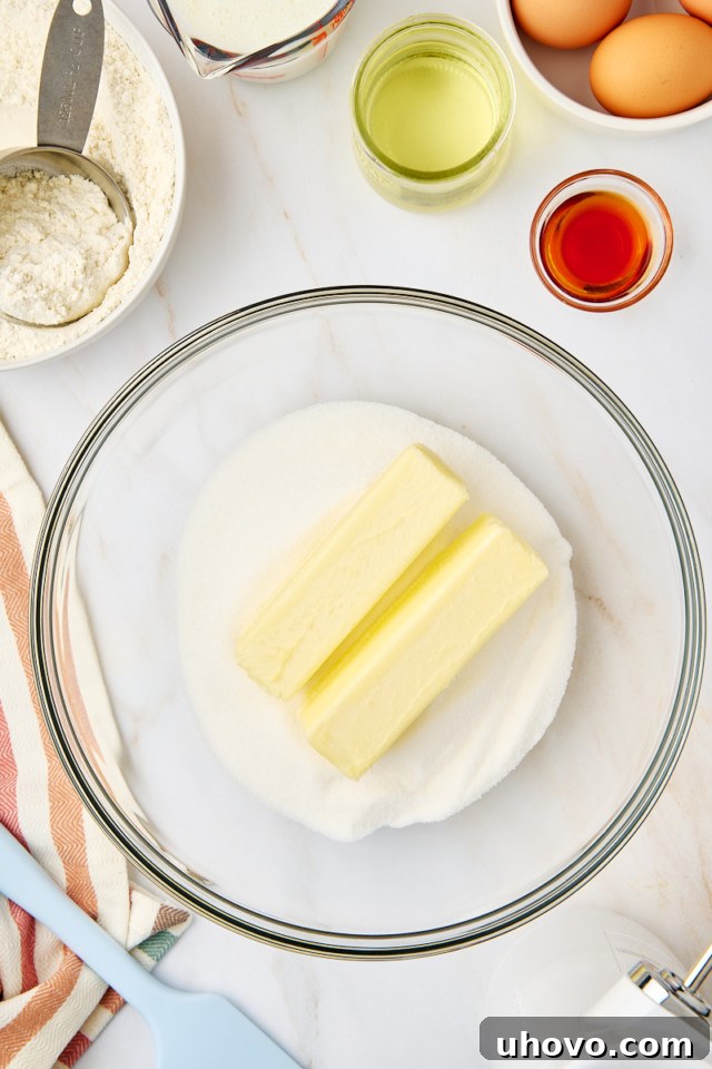 Softened butter and granulated sugar being creamed together in a mixing bowl until light and fluffy.