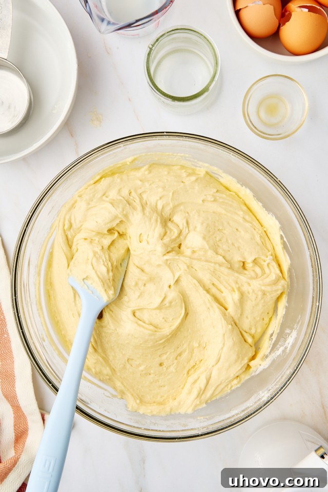 A close-up of fully mixed yellow cake batter in a mixing bowl, showcasing its smooth and slightly thick consistency.