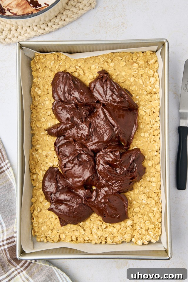 overhead view of chocolate mixture on top of the bottom layer of revel bars in a 9x13 pan