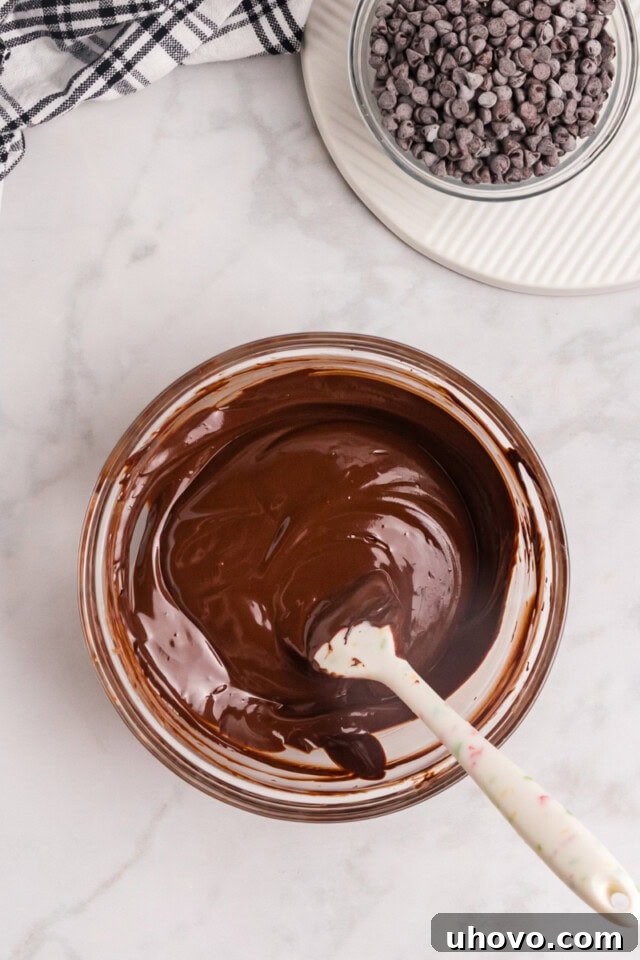 An overhead shot depicting melted bittersweet chocolate and unsalted butter mingling in a clear glass bowl, smooth and ready for the next step.