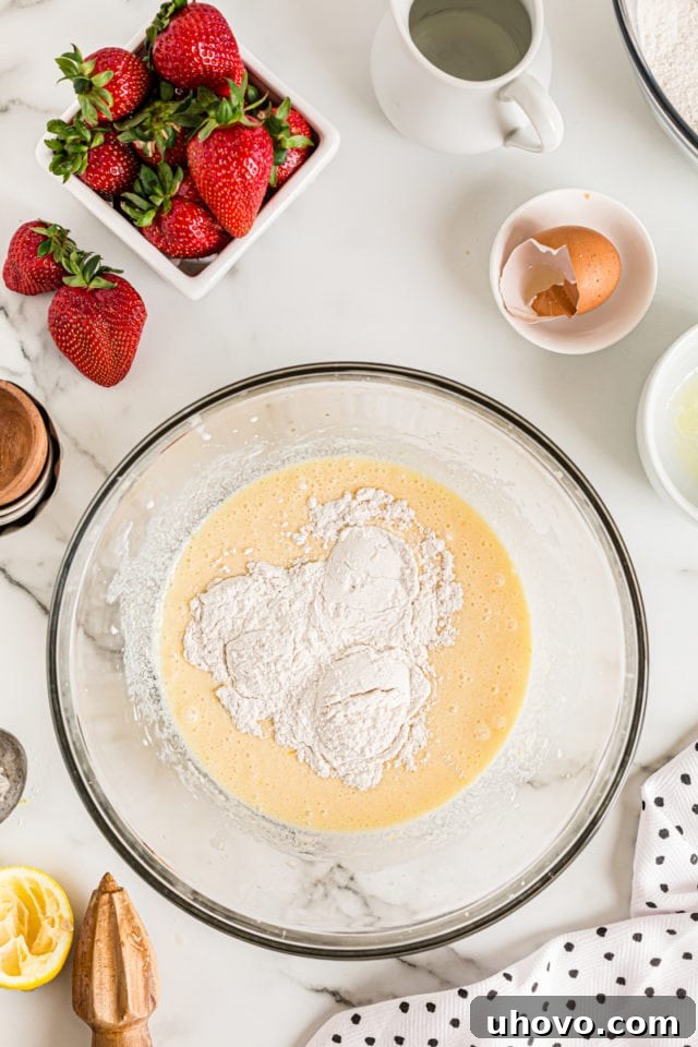 Overhead view of dry ingredients added to wet cake ingredients, illustrating the initial stage of combining the batter.