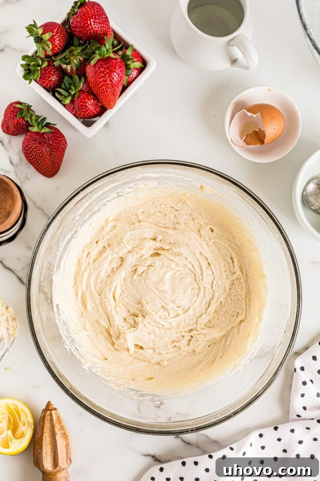 Overhead view of cake batter in a glass mixing bowl, showing its smooth and well-combined consistency before adding fruit.