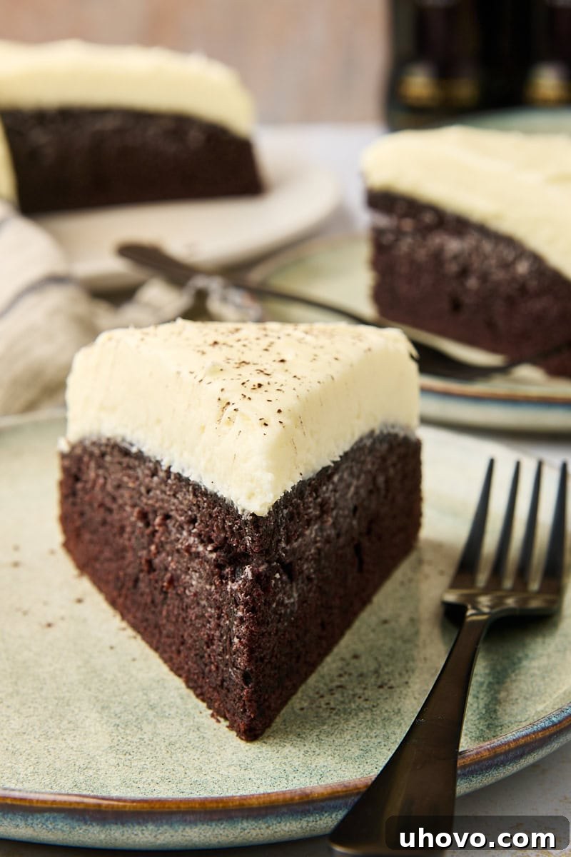 A perfectly sliced Guinness chocolate cake on a plate with a fork, revealing its moist crumb and creamy white frosting.