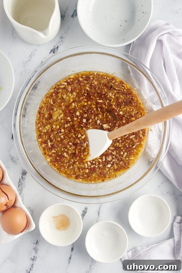 The fully mixed pecan pie filling, a rich, golden-brown mixture with chopped pecans evenly suspended, ready to be poured into the crusts.