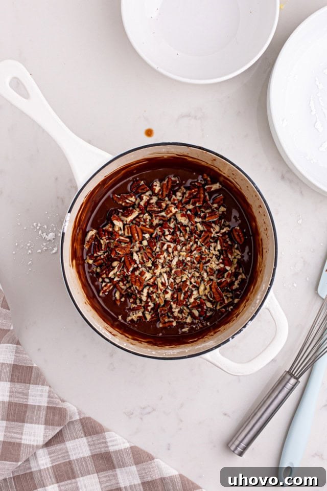 Chopped pecans gently folded into the warm, fudgy Texas sheet cake frosting in a saucepan.