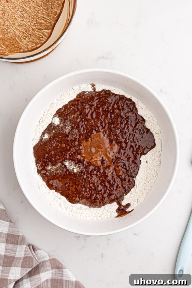 Hot chocolate mixture being poured into the bowl of dry ingredients for the cake batter.
