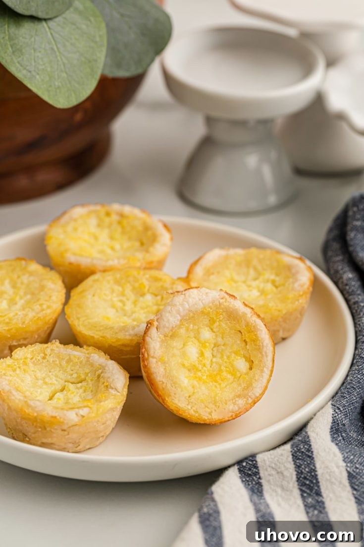 Lemon Chess Tartlets on a white plate, showcasing their perfect golden crust and glistening lemon filling.