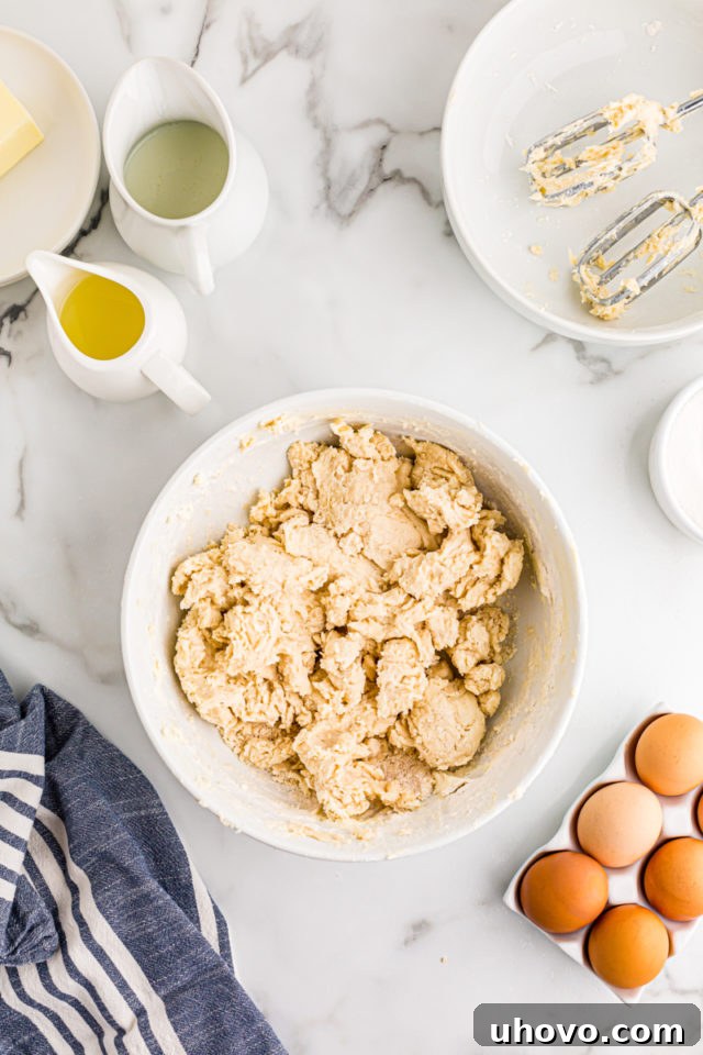 The perfectly mixed, smooth, and slightly golden crust dough for the lemon tarts rests in a white mixing bowl.