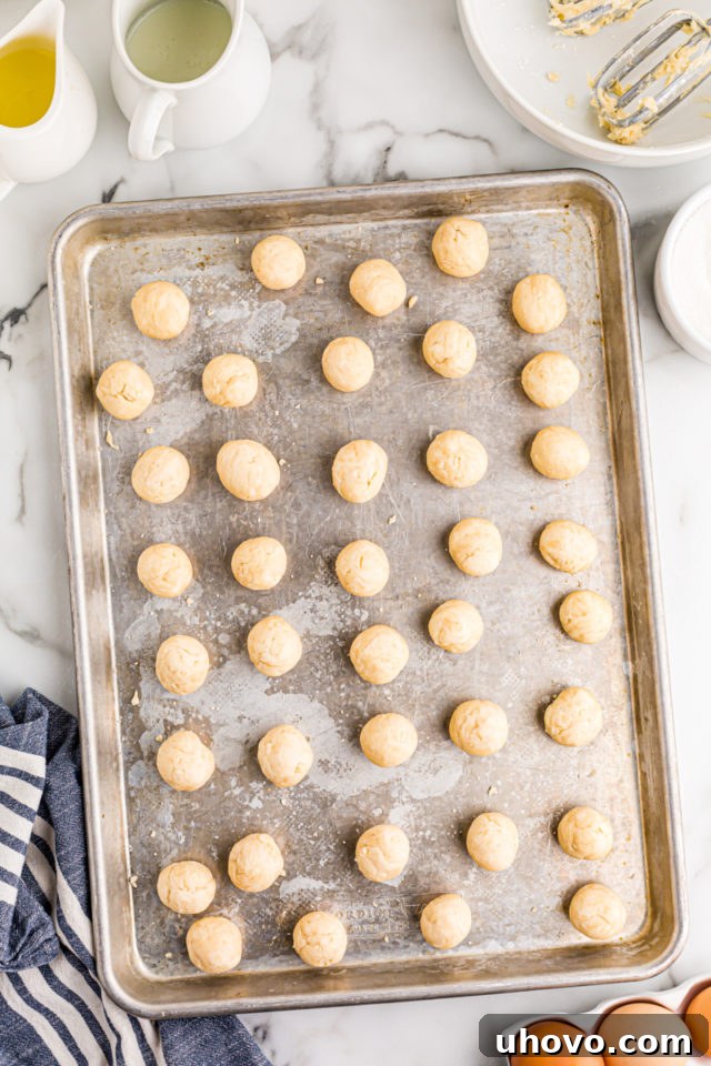 Neatly portioned dough balls for lemon chess tartlets are arranged on a baking sheet, ready for the next step.