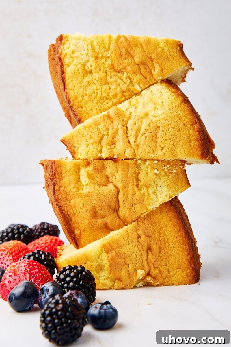 A stack of four slices of whipped cream cake with fresh berries scattered alongside, highlighting its lightness and perfect serving size. This cake is incredibly soft and rich in vanilla flavor, with whipped cream replacing butter for a delicate crumb. Perfect with berries, powdered sugar, or a drizzle of chocolate.