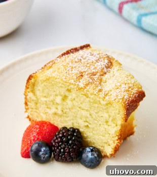 A slice of whipped cream cake and fresh berries on a white plate, showcasing the elegance of the dessert.