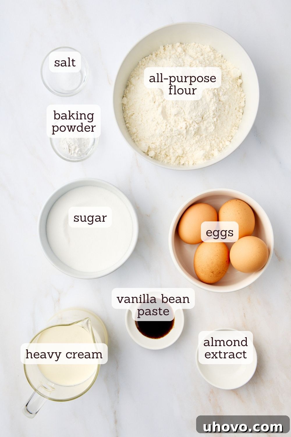 Overhead view of ingredients for whipped cream cake, including flour, sugar, eggs, and heavy cream.