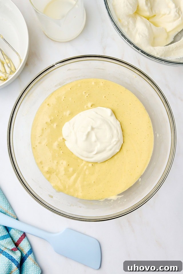 Overhead view of whipped cream being carefully folded into the cake batter.
