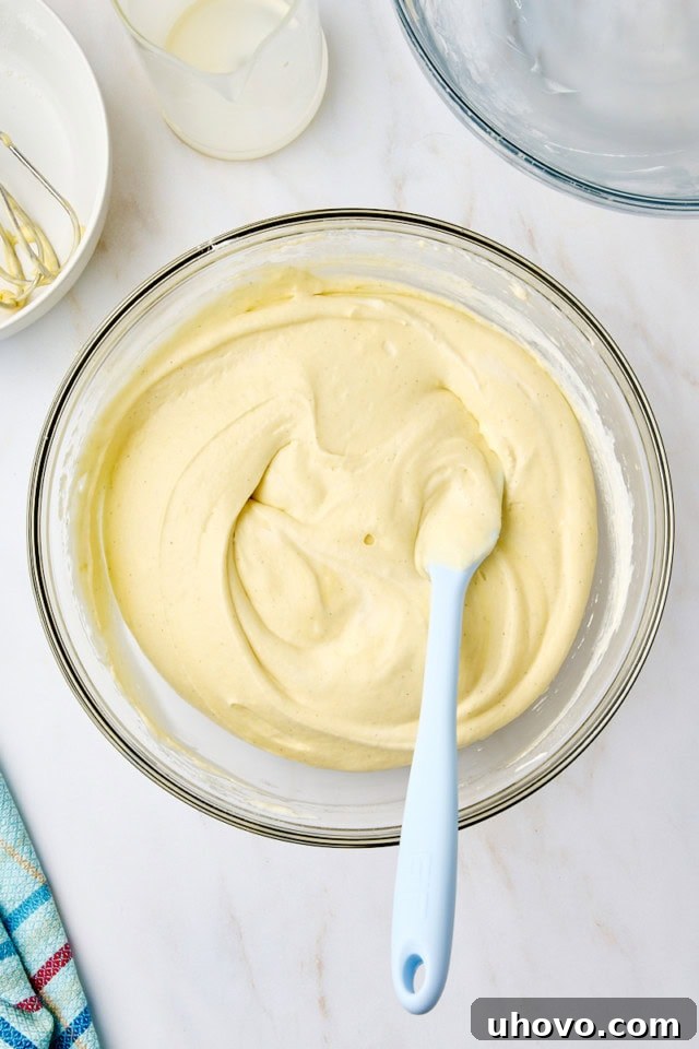 Overhead view of whipped cream cake batter in a glass mixing bowl, mixed just until combined and still airy.