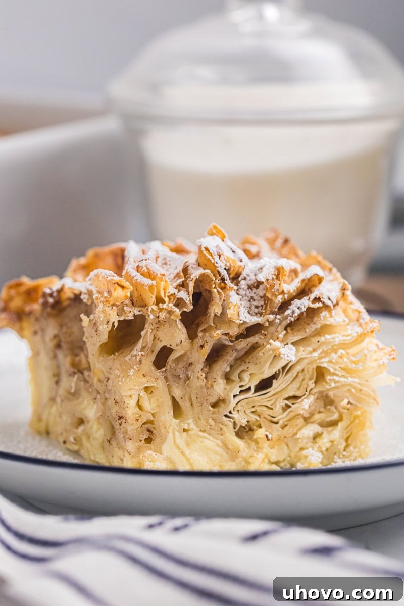 A close-up, mouth-watering view of a single slice of crinkle cake, highlighting its distinct crispy phyllo layers and creamy custard interior.