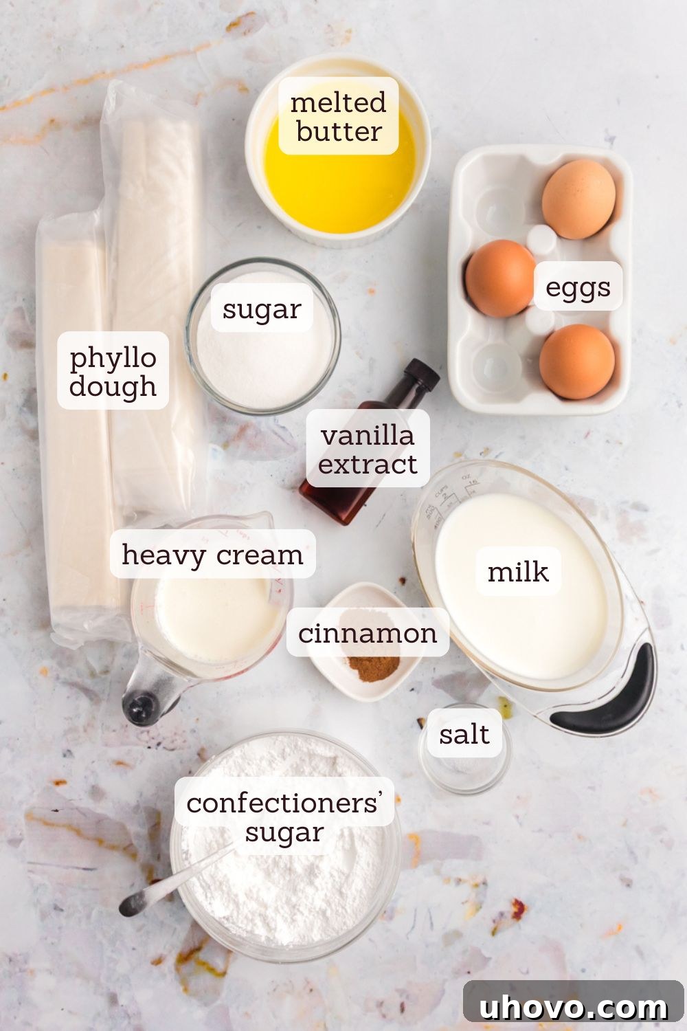 An overhead view showcasing the essential ingredients laid out for making crinkle cake, including phyllo dough, eggs, milk, cream, vanilla, and sugar.