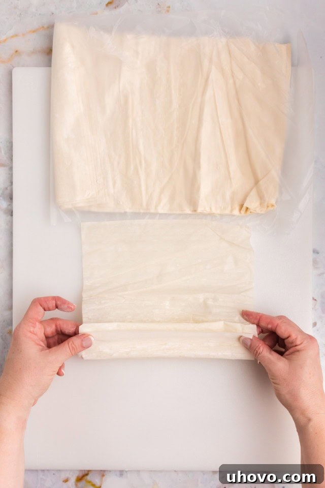 An overhead view demonstrating the technique of loosely folding phyllo dough for crinkle cake, creating gentle waves.