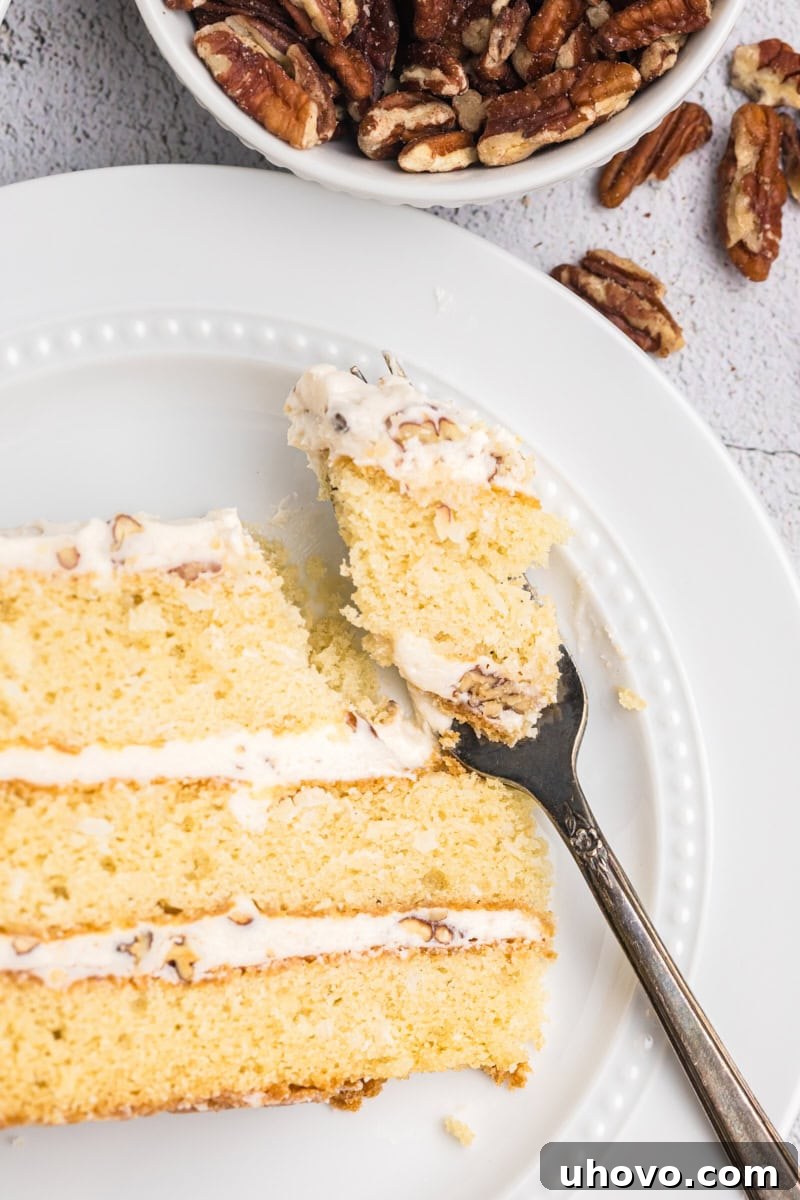 An overhead close-up of a slice of Italian cream cake on a white plate, with a fork holding a perfect bite, emphasizing its texture and appeal.