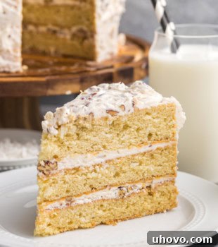 A slice of Italian cream cake on a white plate with the remaining cake in the background, showcasing its delicious appeal.