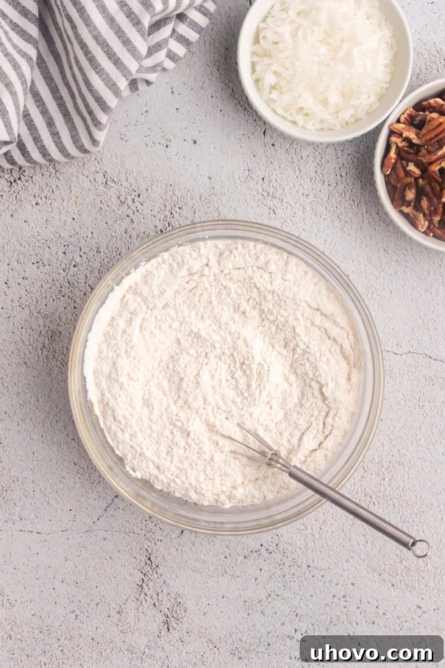 Overhead view of flour and baking soda mixed together in a clear glass bowl, ready for baking.