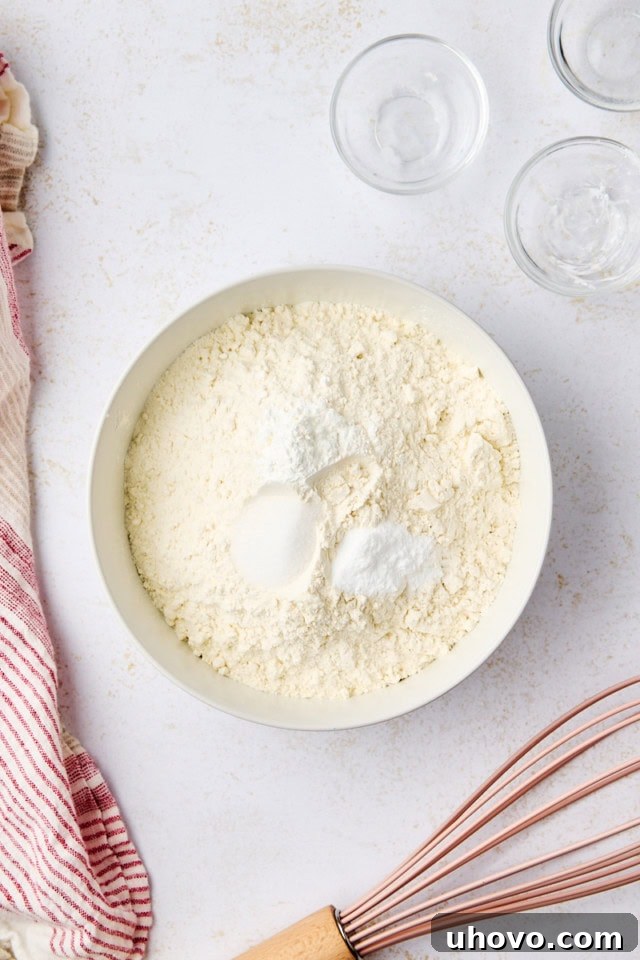 overhead view of flour, cornstarch, baking soda, and salt in a white mixing bowl