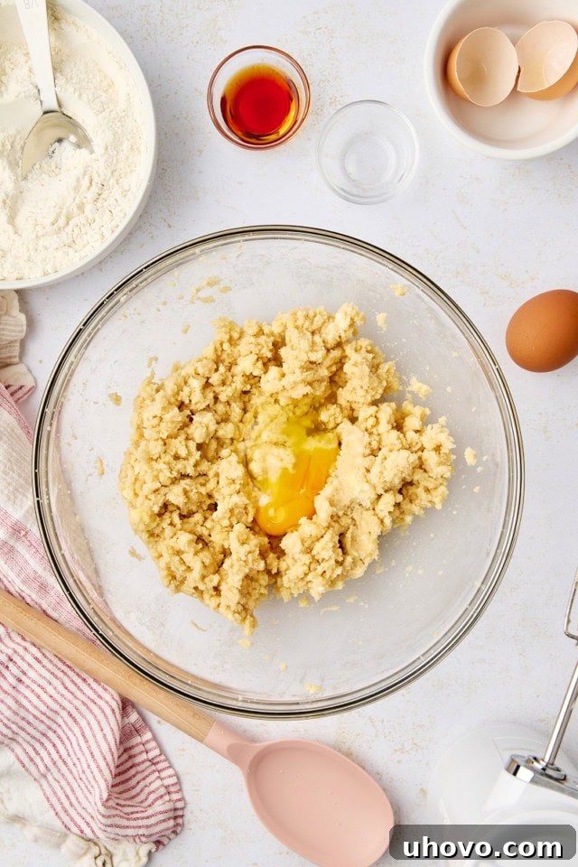 overhead view of egg added to creamed butter and sugars in a glass mixing bowl