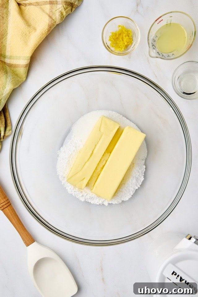 A close-up, overhead view of softened butter and various sugars being creamed together in a glass mixing bowl, demonstrating the initial stage of cookie dough preparation.