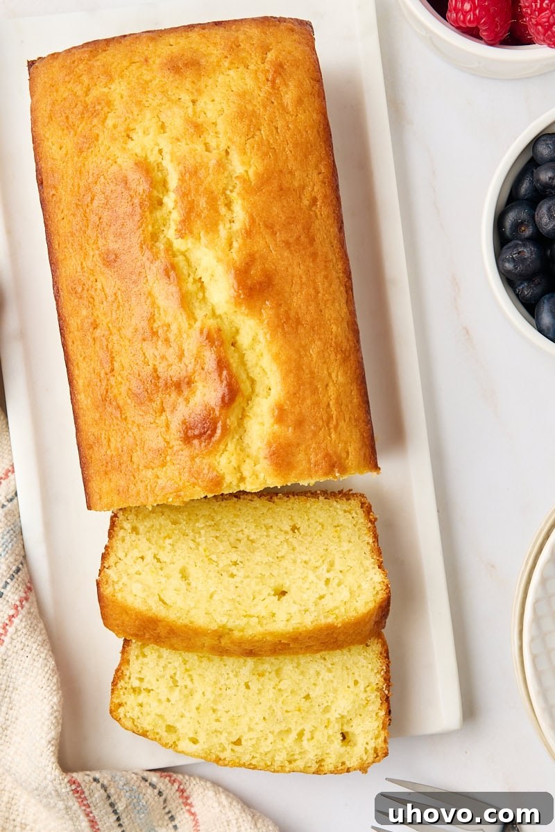 An inviting overhead view of a partially sliced yogurt cake on a pristine white serving plate, highlighting its moist crumb and readiness to be enjoyed.