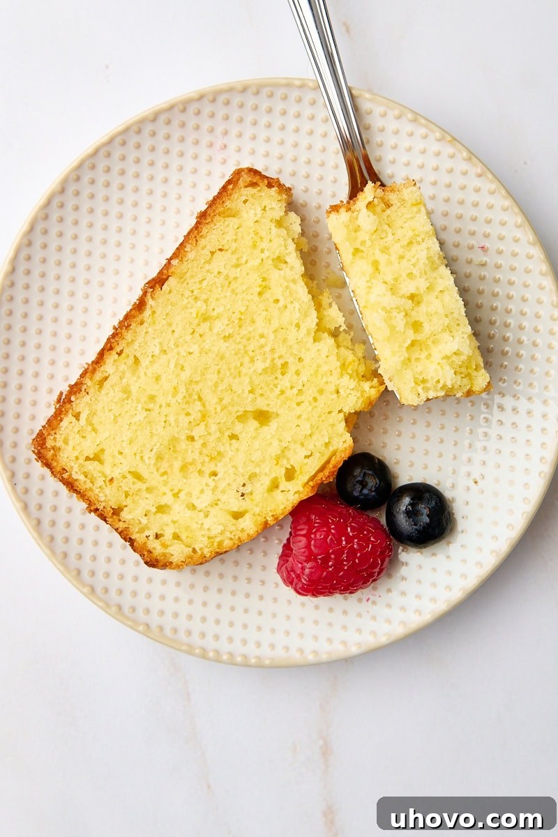 An overhead view of a perfect slice of moist orange yogurt cake on a plate, with a bite on a fork resting gently on the side, highlighting its tender crumb and inviting a taste.