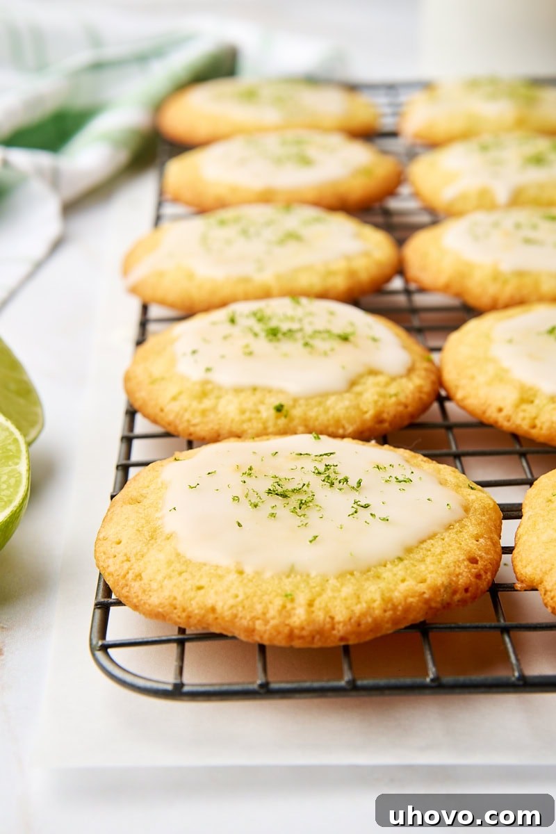 Coconut lime cookies topped with a smooth, sweet lime glaze arranged neatly on a wire rack, ready to be enjoyed.