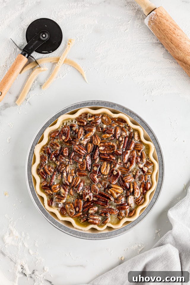 Overhead view of a pecan pie before baking, with the rich filling poured evenly into the chilled pie crust.