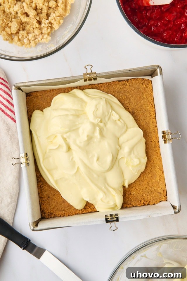 The smooth, creamy cheesecake filling spread evenly over the partially baked graham cracker crust in a square baking pan.