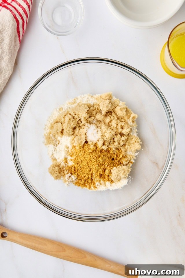 Overhead view of dry ingredients for the crumb topping—all-purpose flour, light brown sugar, a tablespoon of graham cracker crumbs, and a pinch of salt—combined in a mixing bowl.