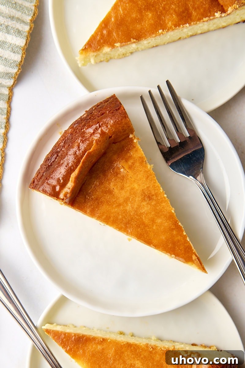 An overhead shot showcasing a perfect slice of New York cheesecake on a white plate, with two more creamy slices partially visible in the background, inviting indulgence.
