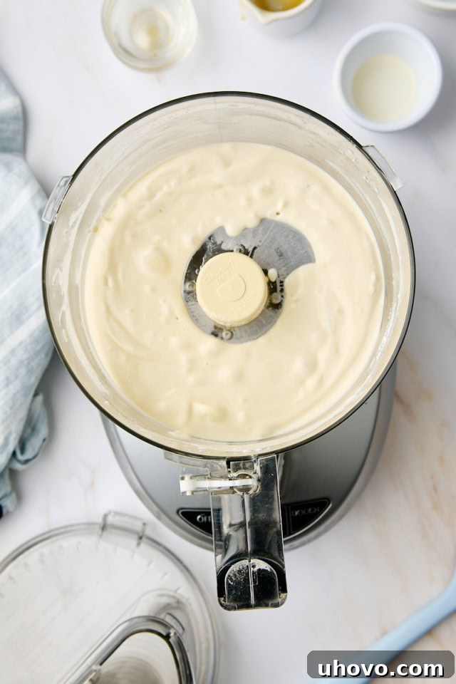 Close-up overhead view of the finished ricotta mousse in the bowl of a food processor, appearing perfectly smooth, creamy, and airy, ready to be portioned.