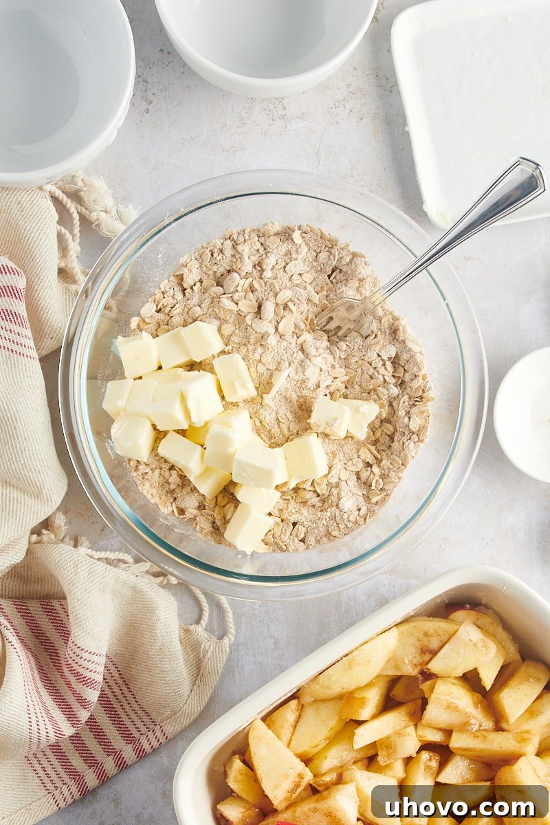 Cold, cubed butter being added to a bowl of flour and spices, ready to be cut into the mixture for the streusel topping.
